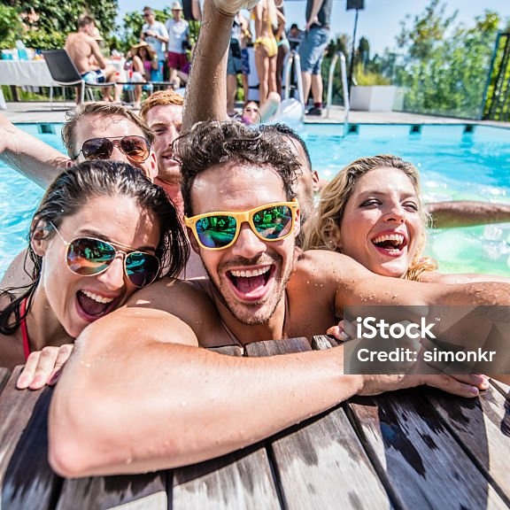 Eine Gruppe junger Menschen hat Spaß am Beckenrand eines Pools.