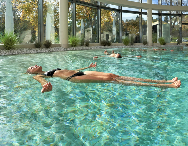 Junge Frau lässt sich rücklings in einem Schwimmbecken treiben